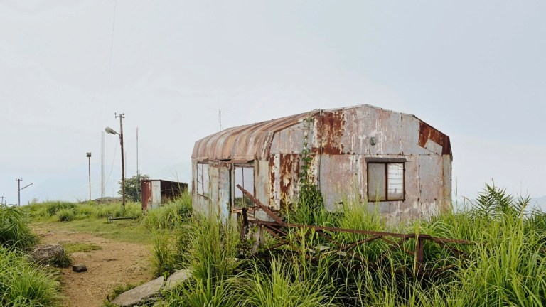 Old abandoned hut at Ilaveezhapoonchira viewpoint surrounded by grasslands in Kottayam, Kerala