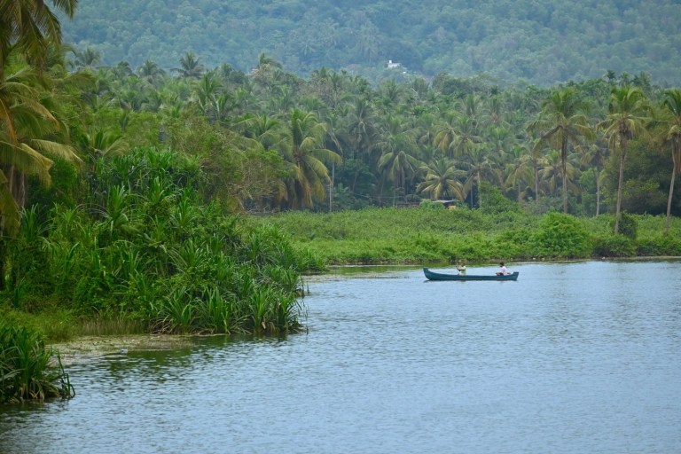 Scenic view of Valiyaparamba Backwaters with a traditional canoe in Kasaragod, Kerala